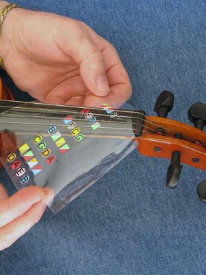 Step 2 slide the violin fingering guide over the fingerboard and under the strings 